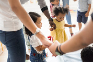 Young diverse kids standing with their parents